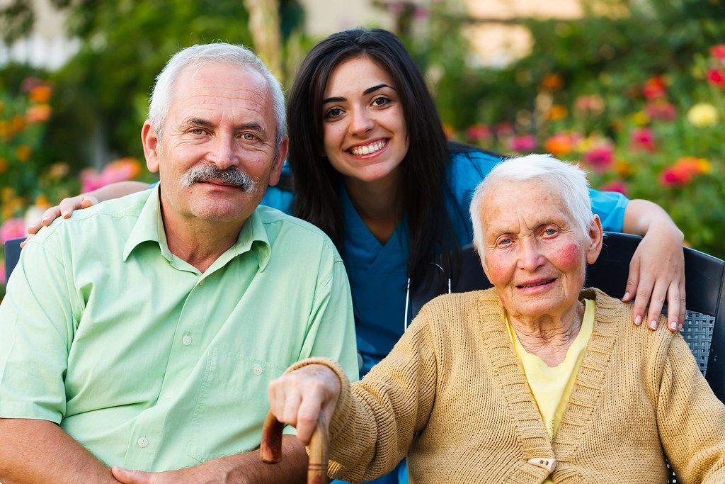 Residents and a caregiver smiling together in the garden